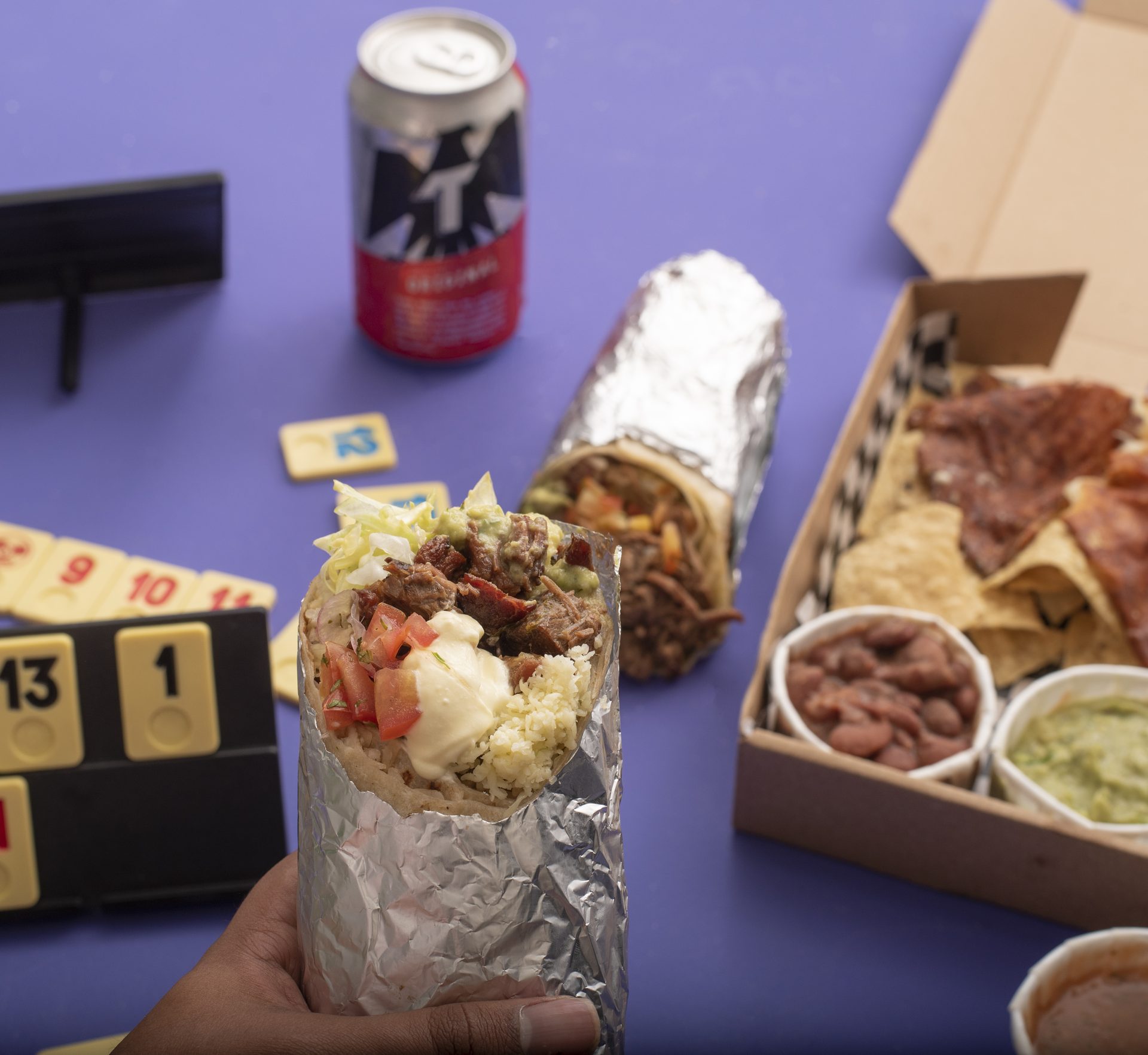 Burro abierto con cartas de Rummikub y caja de nachos